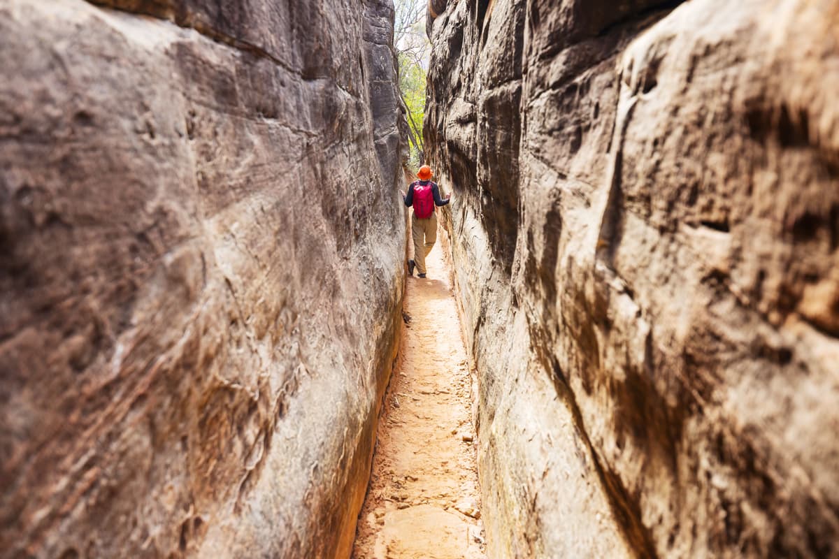 A man hikes through a narrowing gap between cliffs