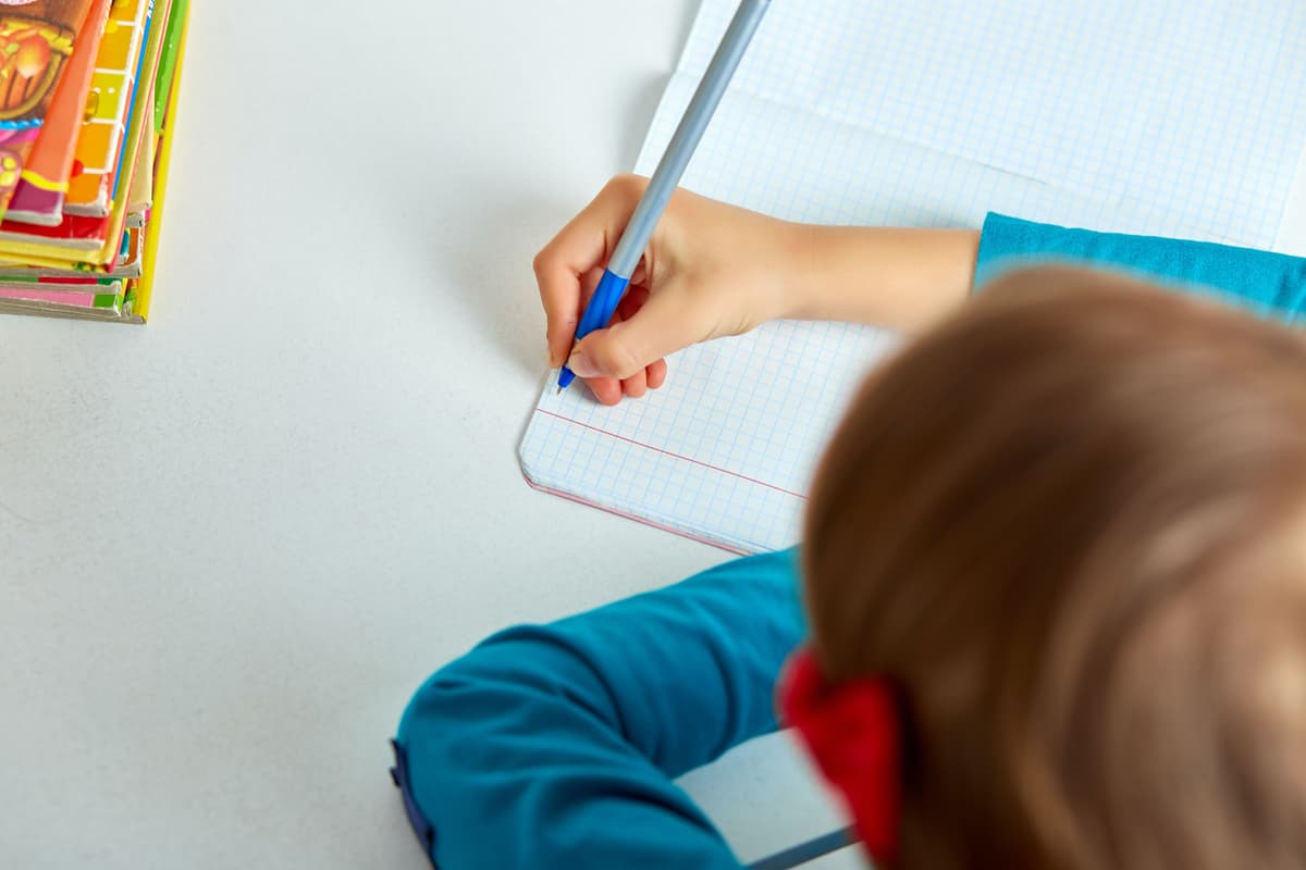 School girl writing with a pen in an exercise book