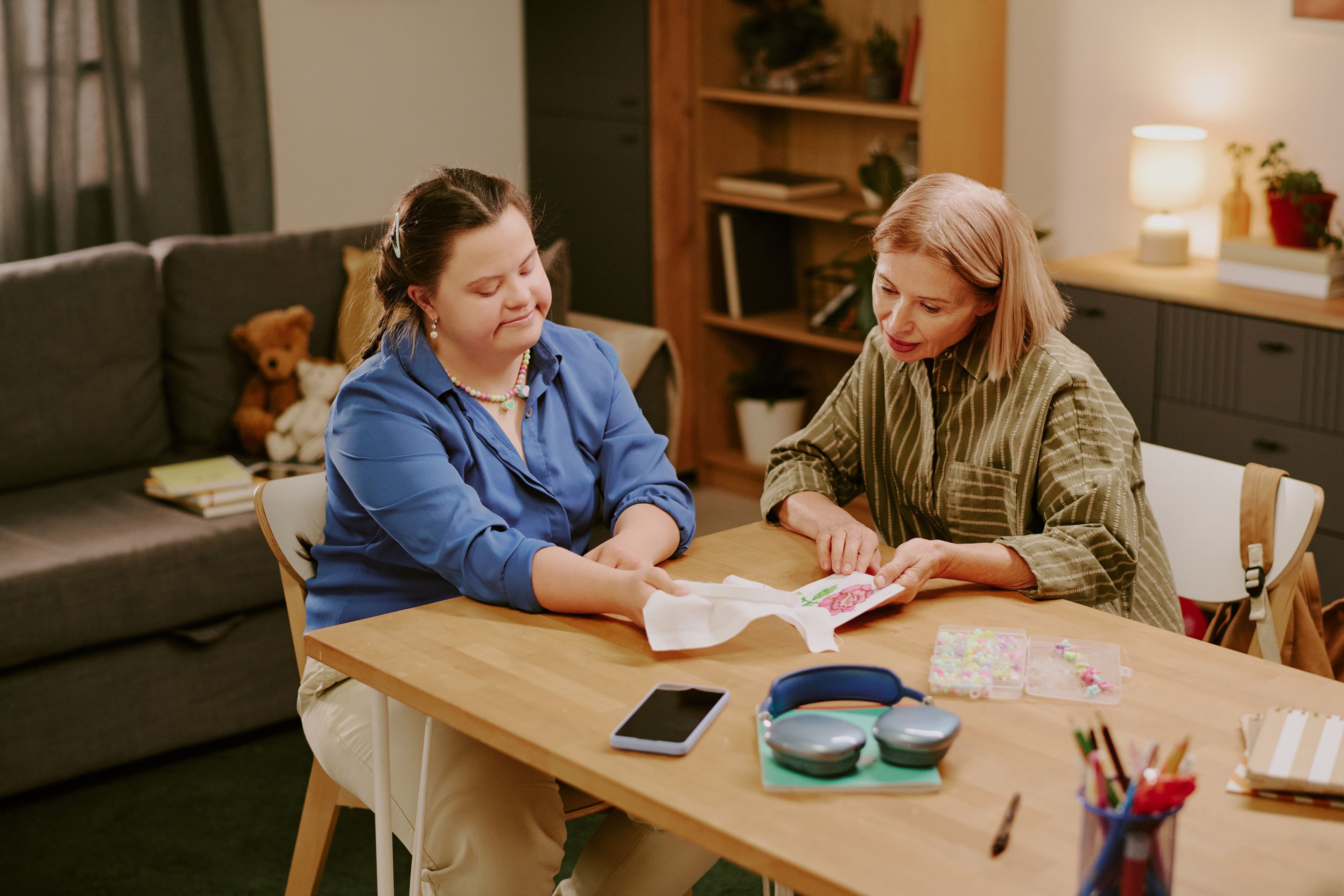 two women sitting at a table looking at crochet