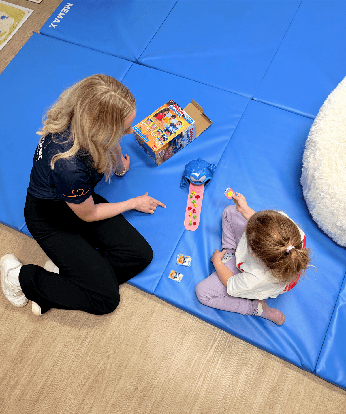 therapist and child on play mat playing with a toy