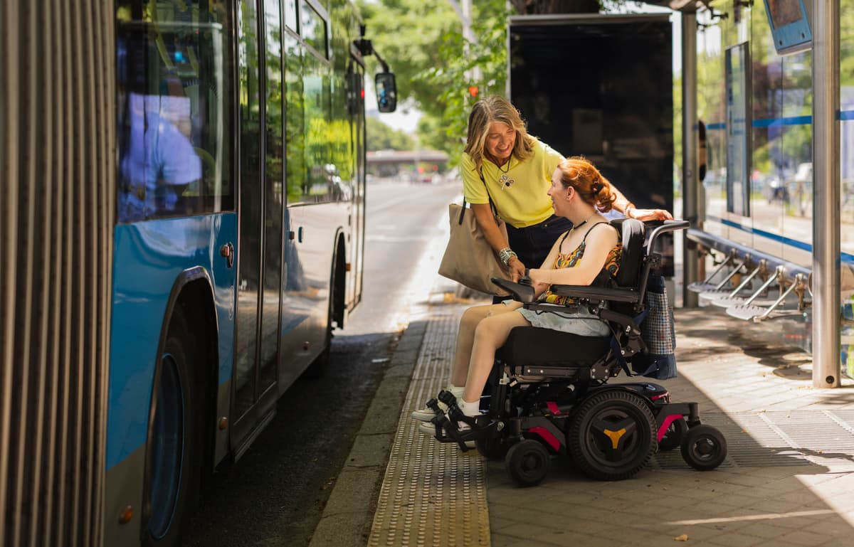 Clinician helping client in wheelchair build capacity to catch public transport